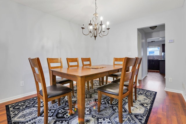 dining room featuring dark wood-type flooring, a chandelier, and sink