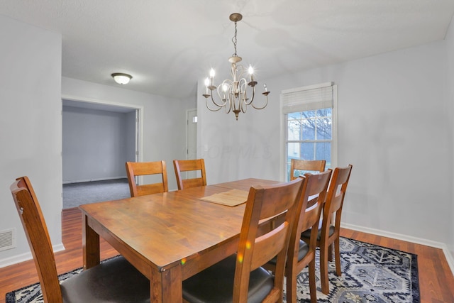 dining area with wood-type flooring and an inviting chandelier