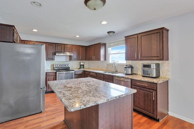 kitchen with a kitchen island, light hardwood / wood-style floors, sink, and appliances with stainless steel finishes