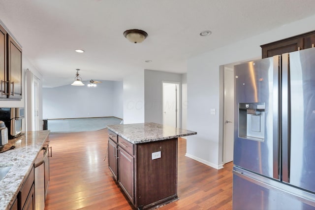 kitchen featuring light stone countertops, stainless steel fridge, dark hardwood / wood-style floors, and a kitchen island