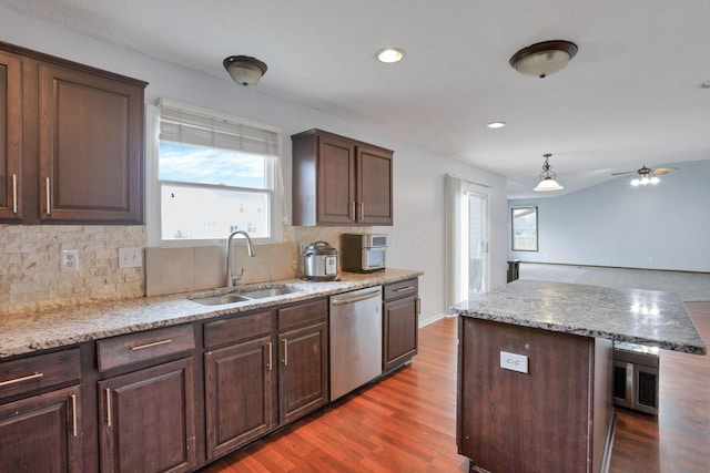 kitchen with stainless steel dishwasher, ceiling fan, dark wood-type flooring, sink, and a kitchen island