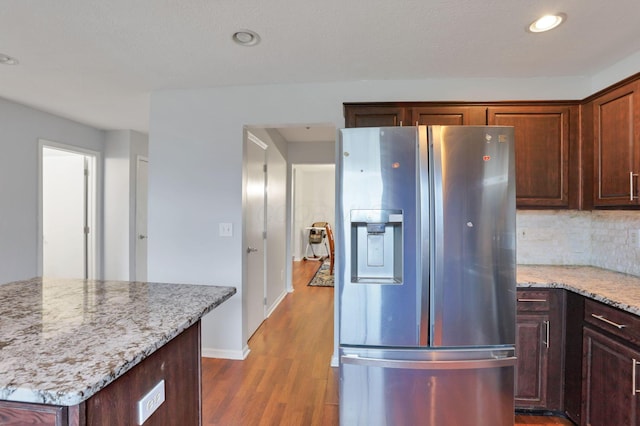 kitchen with tasteful backsplash, stainless steel fridge, dark wood-type flooring, and light stone counters