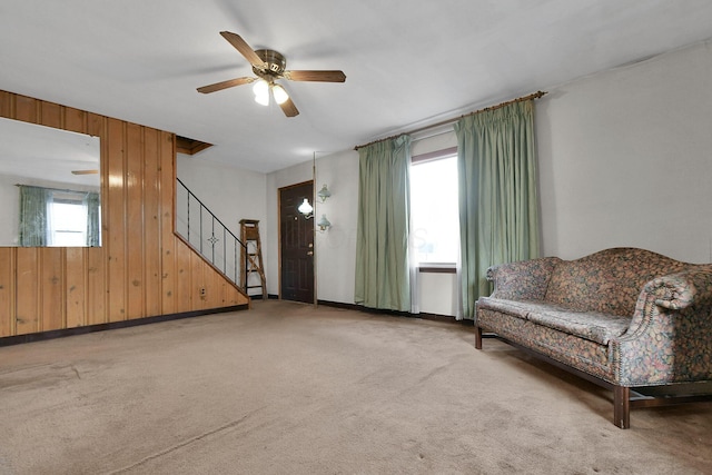 unfurnished room featuring ceiling fan, light colored carpet, and wooden walls