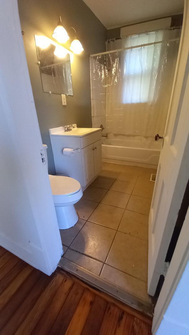 full bathroom with shower / bath combo, toilet, wood-type flooring, and vanity