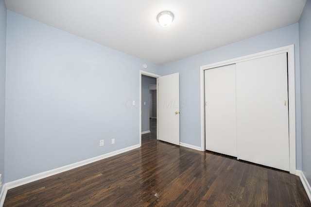 unfurnished bedroom featuring a closet and dark wood-type flooring