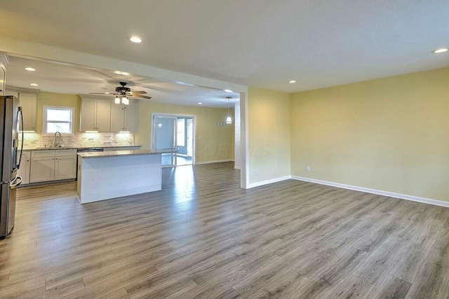 kitchen featuring stainless steel fridge with ice dispenser, a center island, light wood-type flooring, and sink