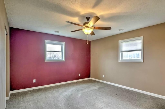 unfurnished room with a wealth of natural light, carpet, a textured ceiling, and ceiling fan