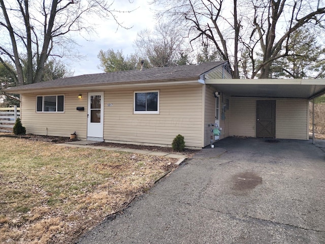 ranch-style home featuring an attached carport, driveway, and a front yard