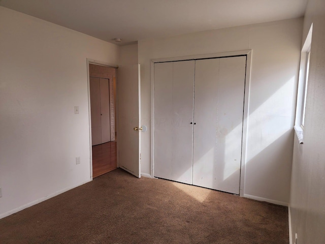 unfurnished bedroom with carpet floors, a closet, and baseboards