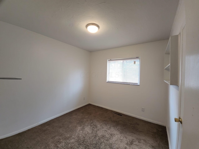 unfurnished room featuring visible vents, baseboards, and dark colored carpet