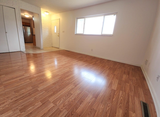 unfurnished room with light wood-style floors, baseboards, and visible vents