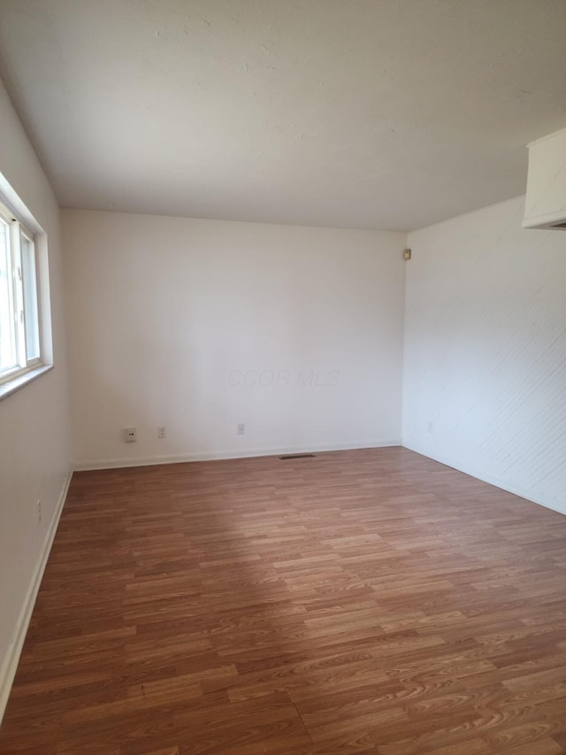 unfurnished room with baseboards and wood finished floors