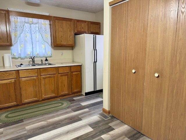 kitchen featuring white refrigerator, dark hardwood / wood-style flooring, sink, and a textured ceiling