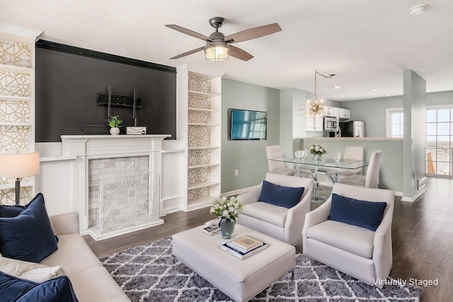 living room featuring a fireplace, dark hardwood / wood-style flooring, and ceiling fan with notable chandelier