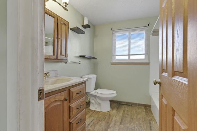 full bathroom with hardwood / wood-style flooring, vanity, toilet, and shower / tub combination