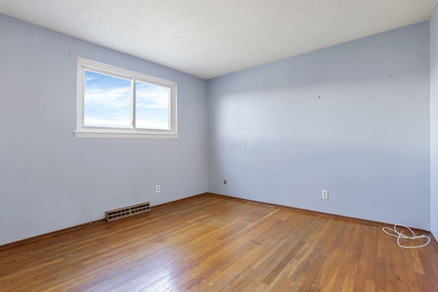 spare room featuring wood-type flooring and a textured ceiling