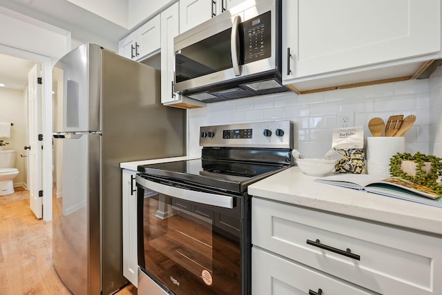 kitchen featuring light stone countertops, decorative backsplash, white cabinetry, and stainless steel appliances