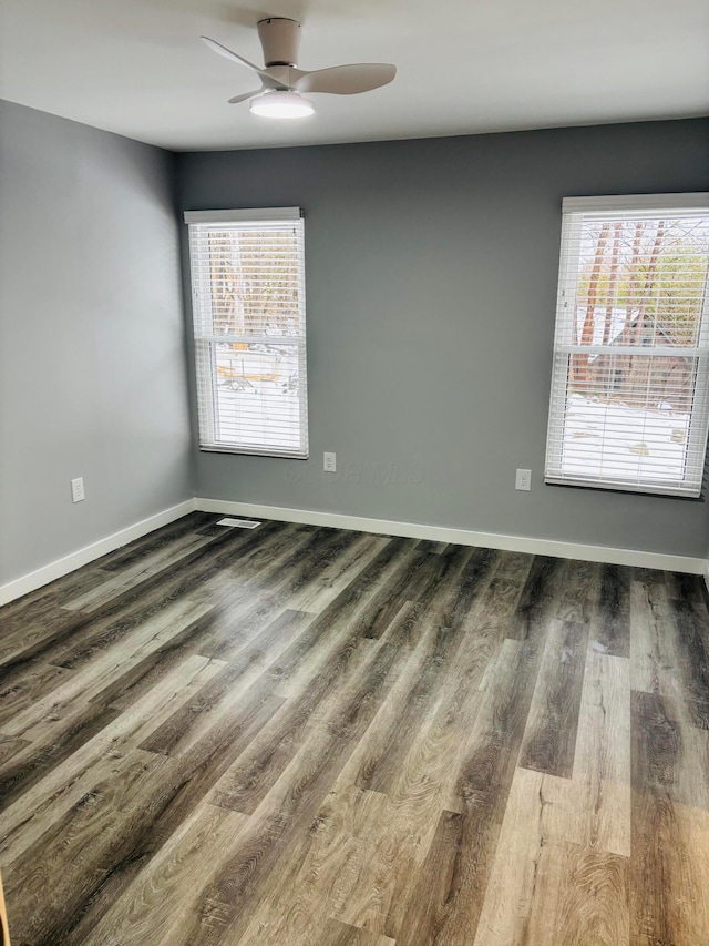 empty room featuring dark hardwood / wood-style flooring, plenty of natural light, and ceiling fan