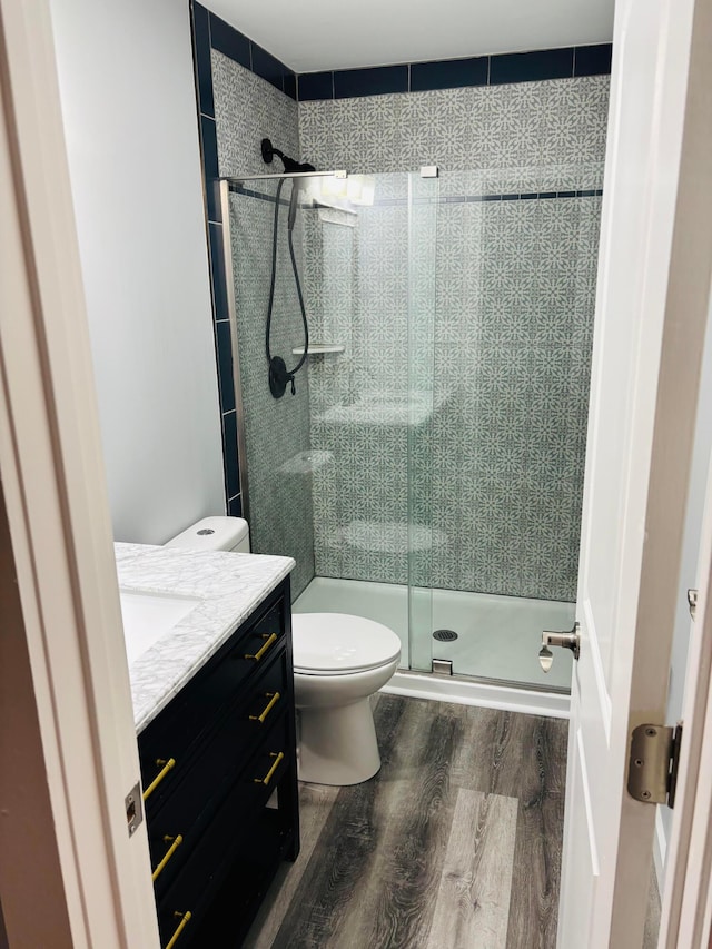 bathroom featuring walk in shower, hardwood / wood-style floors, vanity, and toilet