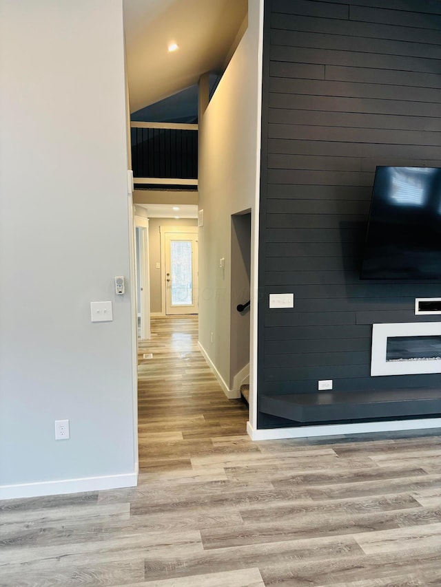 corridor featuring a high ceiling, wood walls, and light hardwood / wood-style flooring