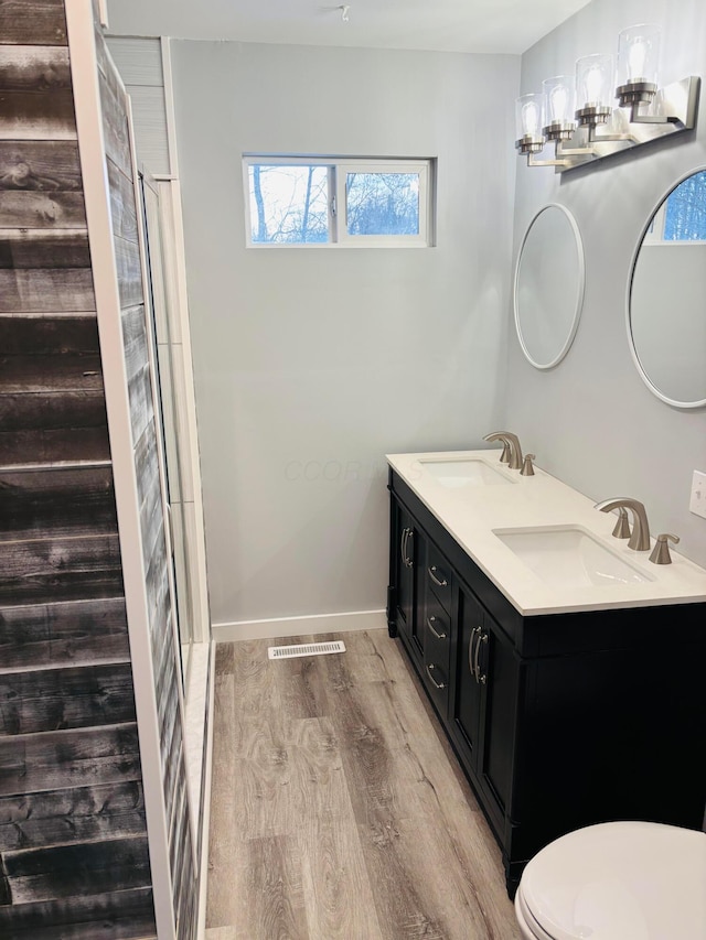 bathroom with vanity, wood-type flooring, a shower with shower door, and toilet