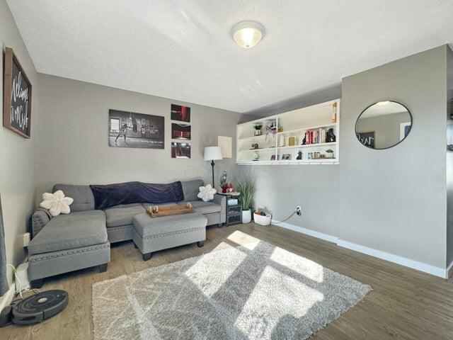 living room featuring built in features, a textured ceiling, and hardwood / wood-style flooring