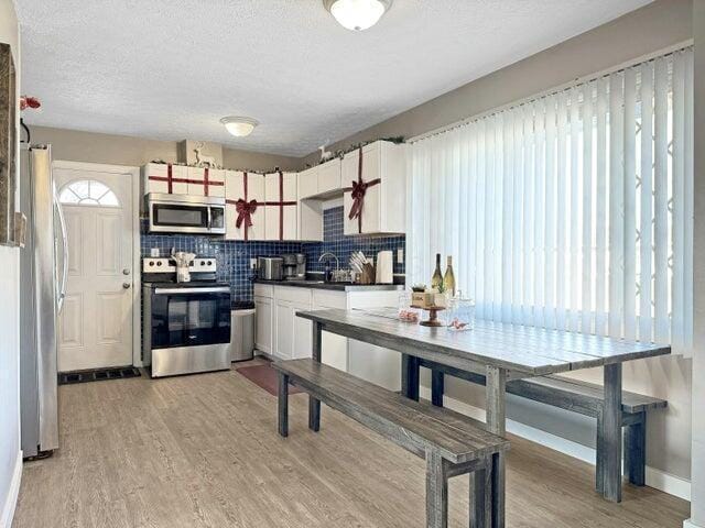 kitchen with appliances with stainless steel finishes, tasteful backsplash, light hardwood / wood-style floors, and sink