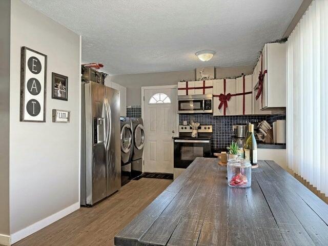 kitchen with hardwood / wood-style floors, decorative backsplash, independent washer and dryer, a textured ceiling, and appliances with stainless steel finishes