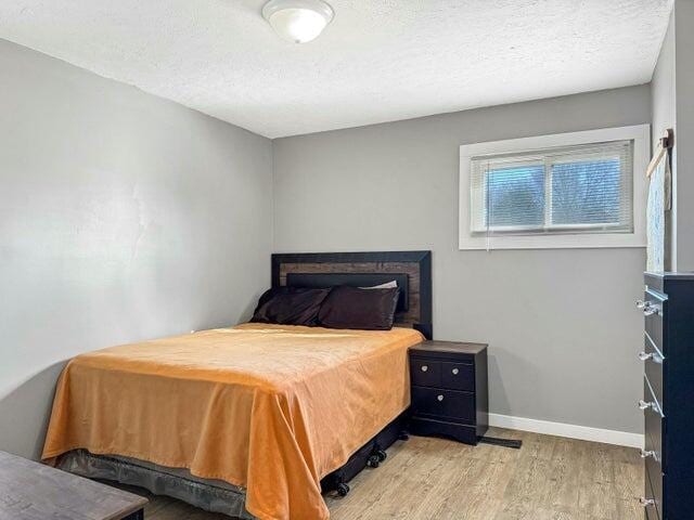 bedroom with a textured ceiling and light hardwood / wood-style flooring