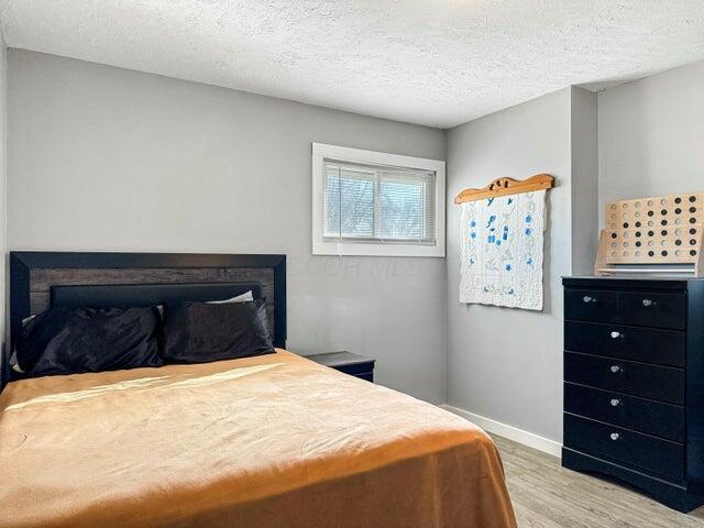 bedroom with light hardwood / wood-style floors and a textured ceiling