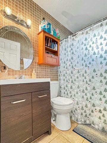 bathroom with vanity, tile patterned flooring, toilet, tile walls, and tasteful backsplash