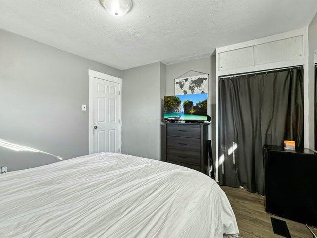 bedroom featuring wood-type flooring, a textured ceiling, and a closet