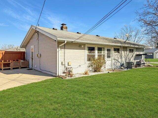 rear view of house with a patio area, a yard, and central AC