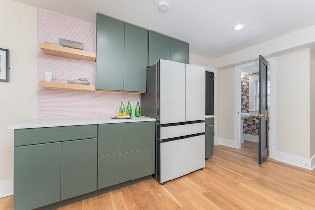 kitchen with backsplash, white fridge, light hardwood / wood-style floors, and green cabinetry