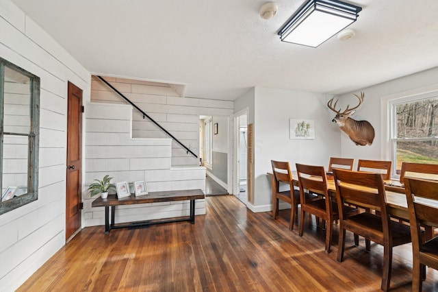 dining space featuring dark hardwood / wood-style flooring and wood walls