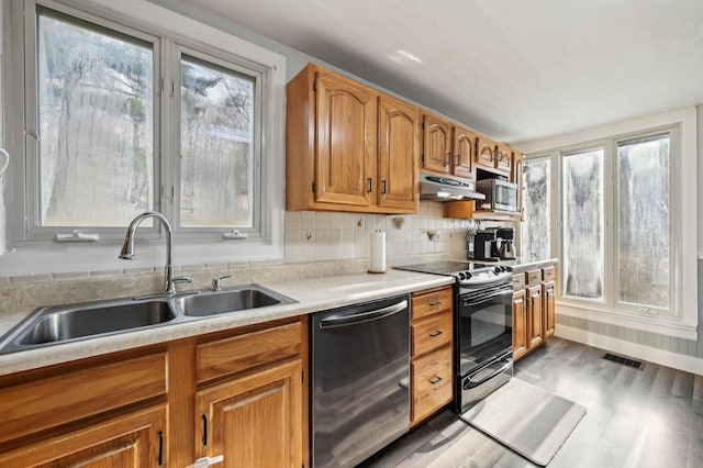 kitchen with light wood-type flooring, backsplash, stainless steel appliances, and sink