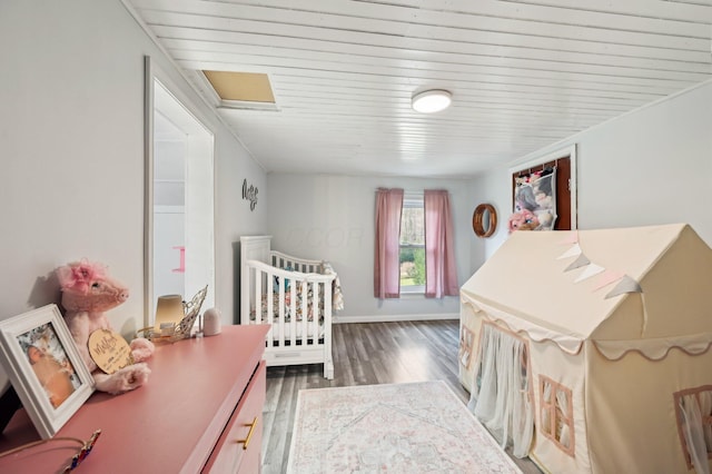 bedroom featuring dark hardwood / wood-style flooring, wooden ceiling, and a crib