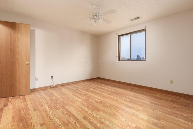 spare room with ceiling fan, light hardwood / wood-style floors, and a textured ceiling