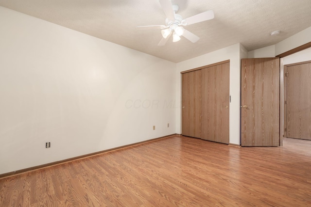 unfurnished bedroom featuring ceiling fan, light wood-type flooring, and a textured ceiling