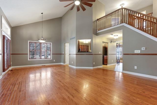 unfurnished living room featuring plenty of natural light, ceiling fan, and high vaulted ceiling