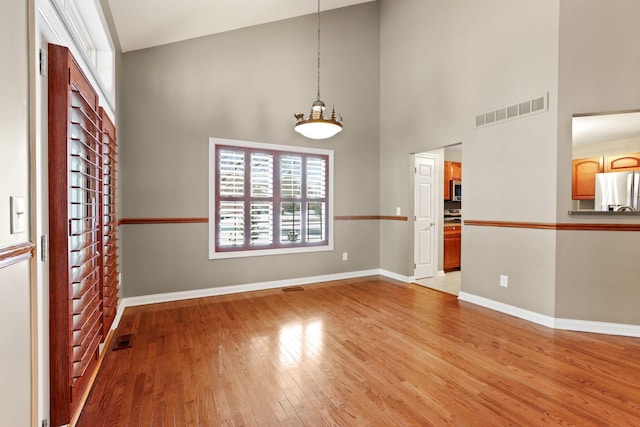 empty room with light wood-type flooring and high vaulted ceiling