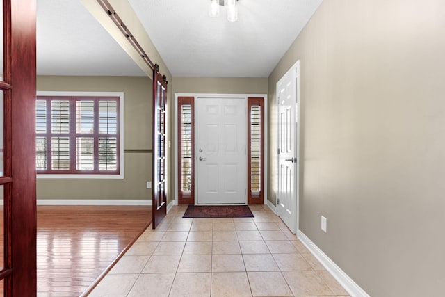 foyer entrance featuring a barn door and light tile patterned flooring