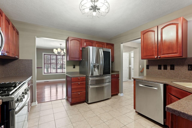 kitchen with tasteful backsplash, a notable chandelier, decorative light fixtures, light tile patterned flooring, and appliances with stainless steel finishes