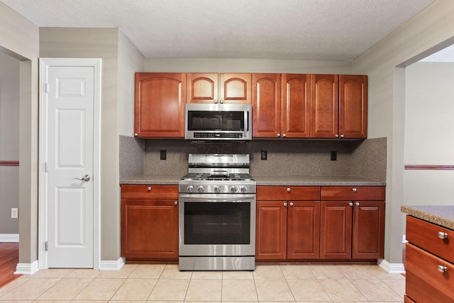 kitchen featuring light tile patterned floors, a textured ceiling, appliances with stainless steel finishes, and tasteful backsplash