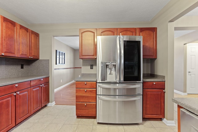 kitchen featuring stainless steel fridge with ice dispenser, a textured ceiling, light tile patterned floors, and tasteful backsplash