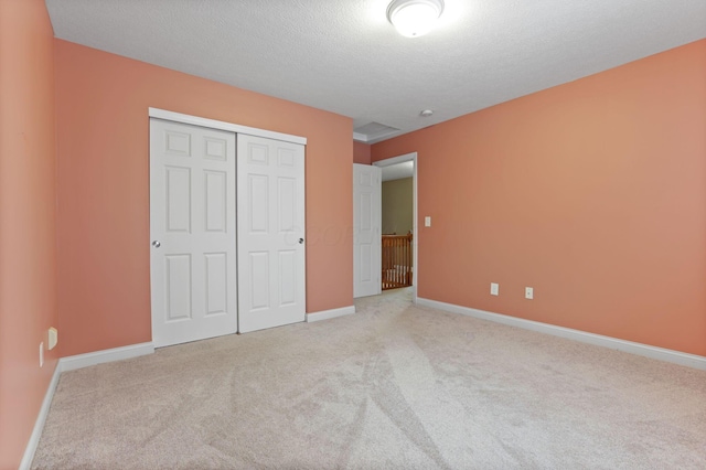 unfurnished bedroom featuring a closet, light colored carpet, and a textured ceiling