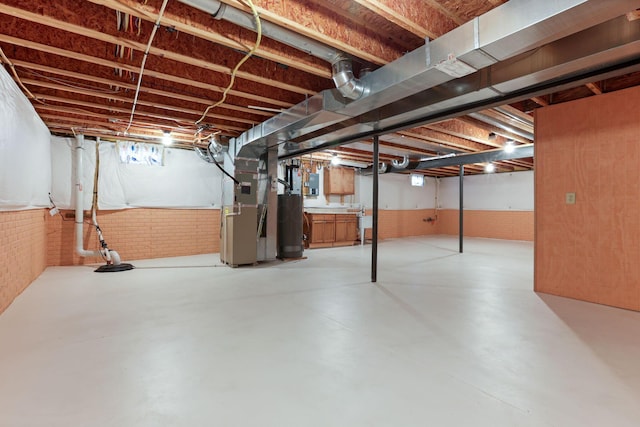 basement with heating unit, water heater, electric panel, and brick wall