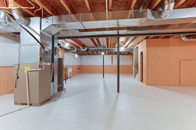 basement with gas water heater, brick wall, and heating unit