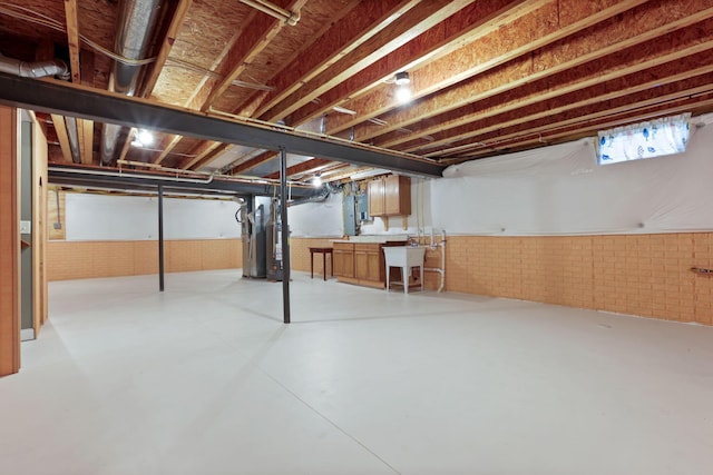 basement featuring water heater, sink, and brick wall