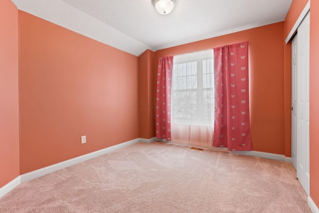 carpeted empty room featuring vaulted ceiling